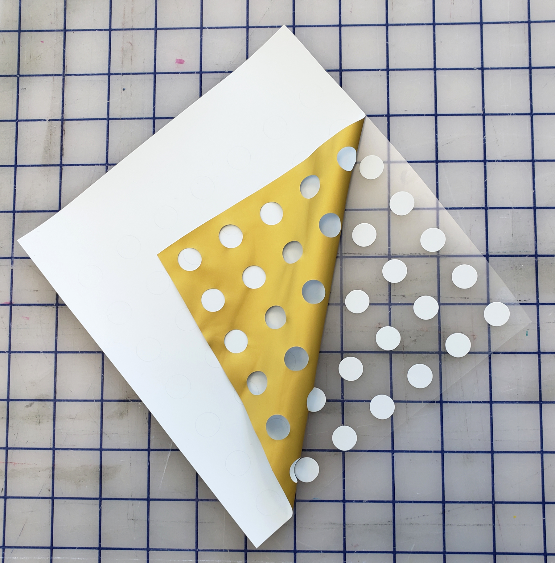 The dots, now cut in heat transfer vinyl being weeded by pulling the excess out and leaving the dots behind.